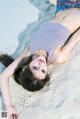 A woman laying on the sand on a beach.