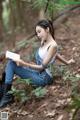 A woman sitting in the woods reading a book.