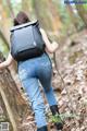 A woman with a backpack walking through the woods.