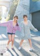 A couple of women standing next to each other on a sidewalk.