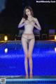 A woman in a bikini standing next to a swimming pool.