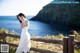 A woman in a white dress standing by a wooden fence.