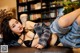 A woman laying on top of a brown leather couch.