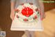 A woman holding a white cake with red and green decorations.