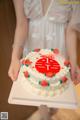 A woman holding a white cake with red and green decorations.