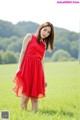 A woman in a red dress standing in a field.