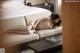 A woman laying on a couch in a hotel room.