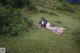 A woman laying on a blanket in a grassy field.