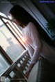 A woman leaning against a railing looking out a window.