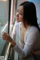 A woman leaning against a window looking out the window.