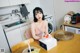 A woman sitting at a table with a cake in front of her.