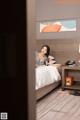 A woman sitting on a bed in a hotel room.