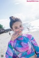 A young woman wearing sunglasses on a beach.