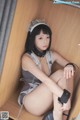 A woman in a maid outfit is sitting on a wooden bench.