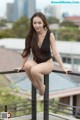 A woman in a black bathing suit sitting on a railing.