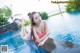 A woman in a pink bikini sitting on the edge of a swimming pool.