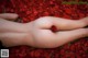 A naked woman laying on a bed of red rose petals.