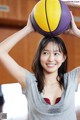 A woman holding a basketball over her head.