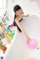 A woman in a bathtub with balloons in it.