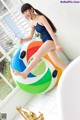 A woman in a bathing suit is sitting on an inflatable ball.