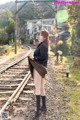 A woman in a school uniform standing on a train track.