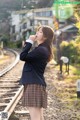 A woman in a school uniform standing on a train track.