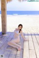 A woman in a white bikini sitting on a wooden dock.