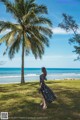 A woman in a black dress standing in front of a palm tree.