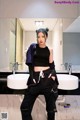 A woman standing in front of a bathroom sink.