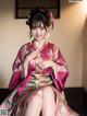 A woman in a pink and green kimono sitting on a bed.