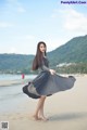 A woman in a gray dress standing on a beach.