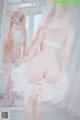 A woman in a white lingerie standing in front of a mirror.
