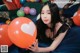 A woman laying on a bed holding a bunch of balloons.