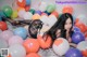 A woman laying on top of a bed covered in balloons.