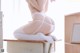 A woman in a white lingerie sitting on a desk.