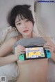 A woman laying in bed holding a Nintendo Switch.