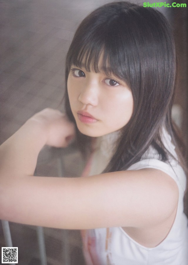 A woman with long black hair leaning against a wall.