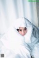 A woman laying in bed under a white blanket.