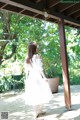 A woman in a white dress standing on a patio.