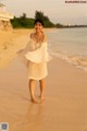 A woman in a white dress standing on a beach.