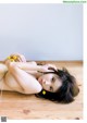 A naked woman laying on a wooden floor with a string around her neck.