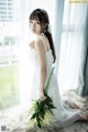 A woman in a white dress holding a bunch of flowers.