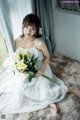 A woman in a white dress holding a bouquet of flowers.