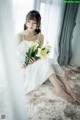 A woman in a white dress holding a bouquet of flowers.