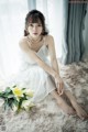 A woman in a white dress sitting on a white rug.