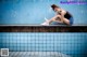 A woman sitting on the edge of a swimming pool.