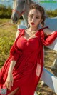 A woman in a red dress standing next to a white horse.