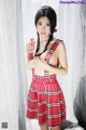 A woman in a red and black plaid dress posing for a picture.