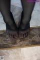 A pair of feet that are standing on a tiled floor.