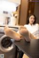 A woman sitting on top of a table next to a washing machine.